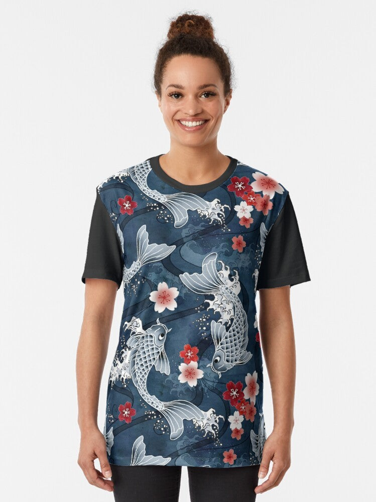 Graphic t-shirt featuring a koi fish swimming amidst sakura blossoms in a blue watercolor-style design - Women