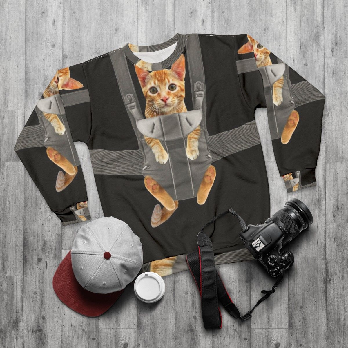 Monty the cat wearing a baby carrier on a sweatshirt - flat lay