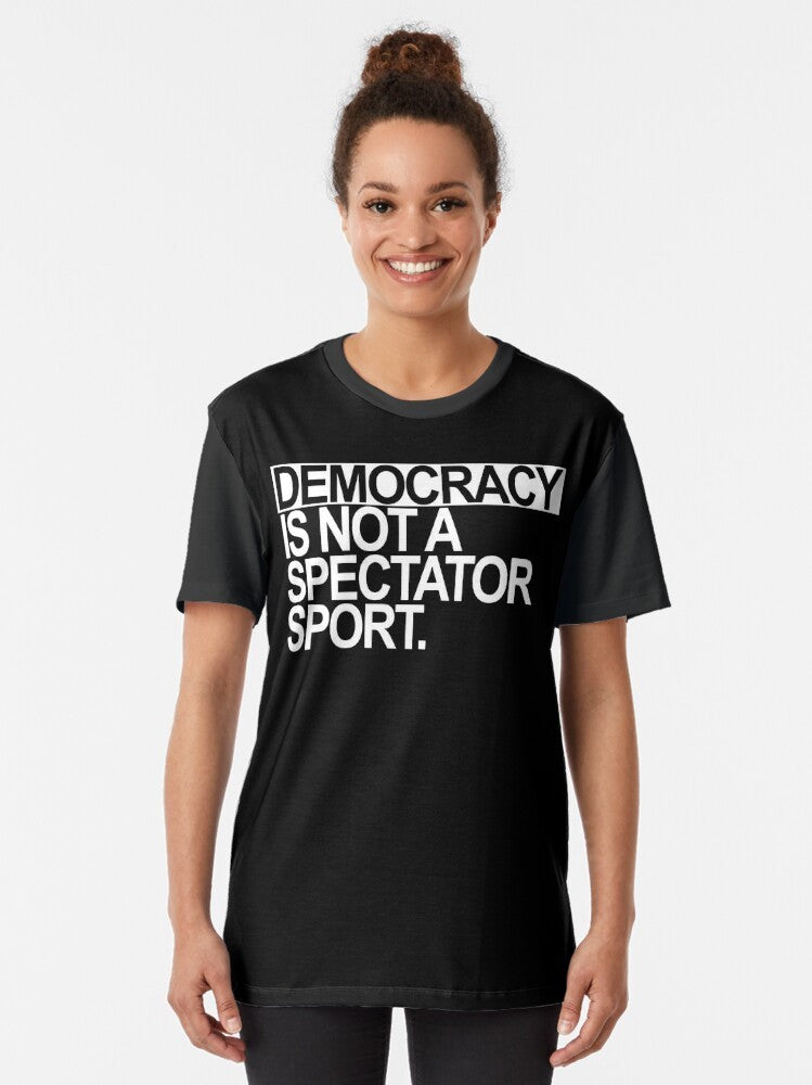 A white t-shirt with the text "Democracy is NOT a Spectator Sport" in bold, black letters. - Women