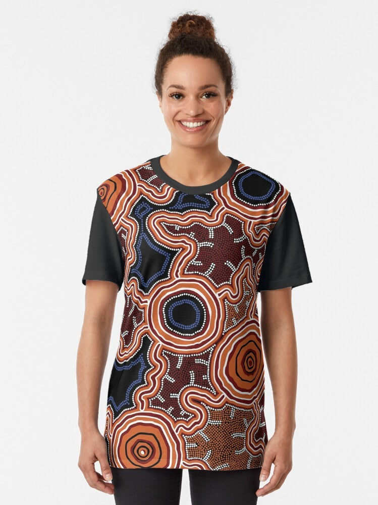 Authentic Aboriginal Art Pathways to Water Graphic T-Shirt featuring traditional indigenous artwork with dots, kangaroos, emus, and earth tones. - Women