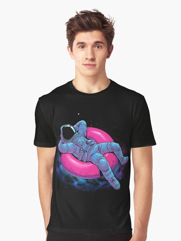 A graphic t-shirt design featuring a floating astronaut in a dreamy, cosmic space scene with stars, nebula, and other celestial elements. - Men