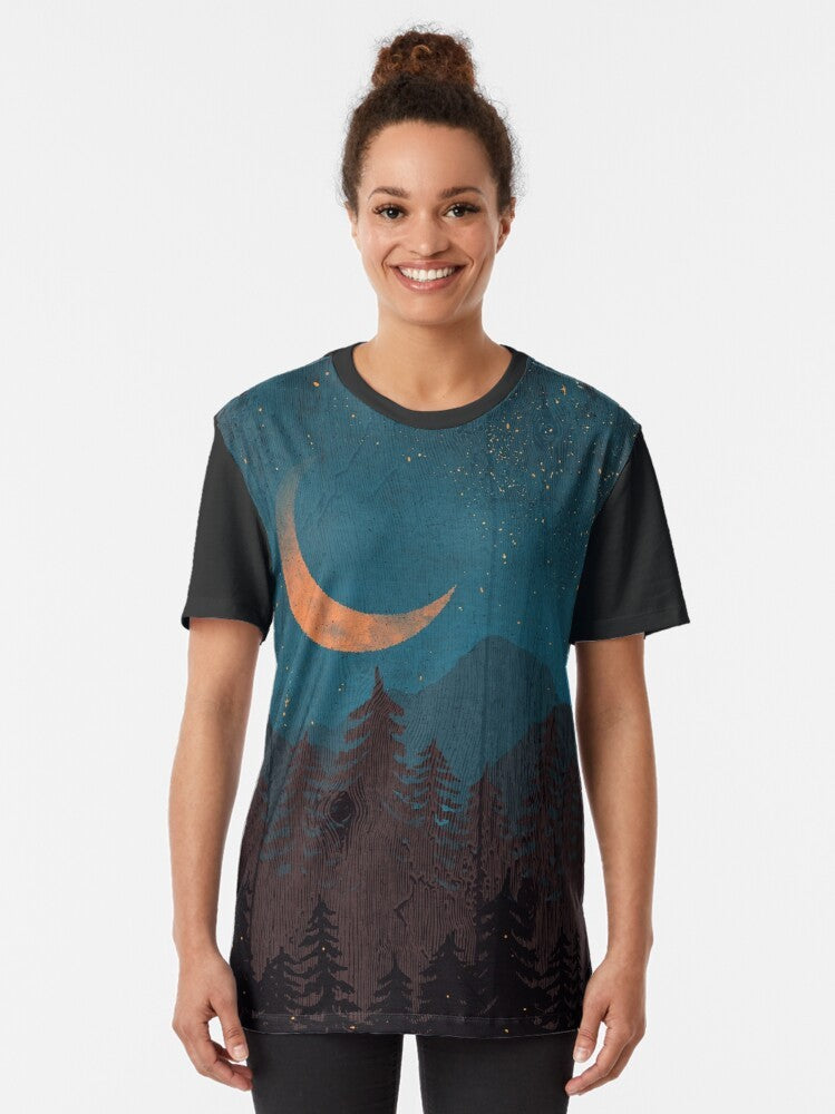 Graphic t-shirt featuring a landscape with a moon, stars, lightning, and fireflies in a forest setting - Women