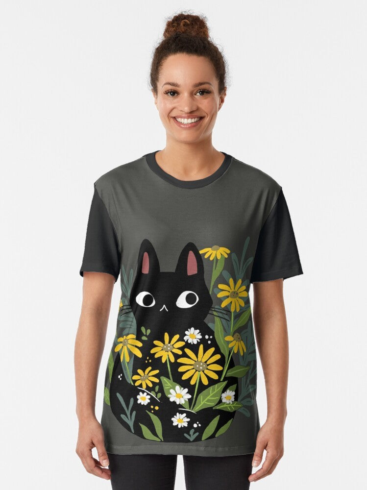 A charming graphic t-shirt featuring a black cat surrounded by vibrant flowers, creating a whimsical and nature-inspired design. - Women