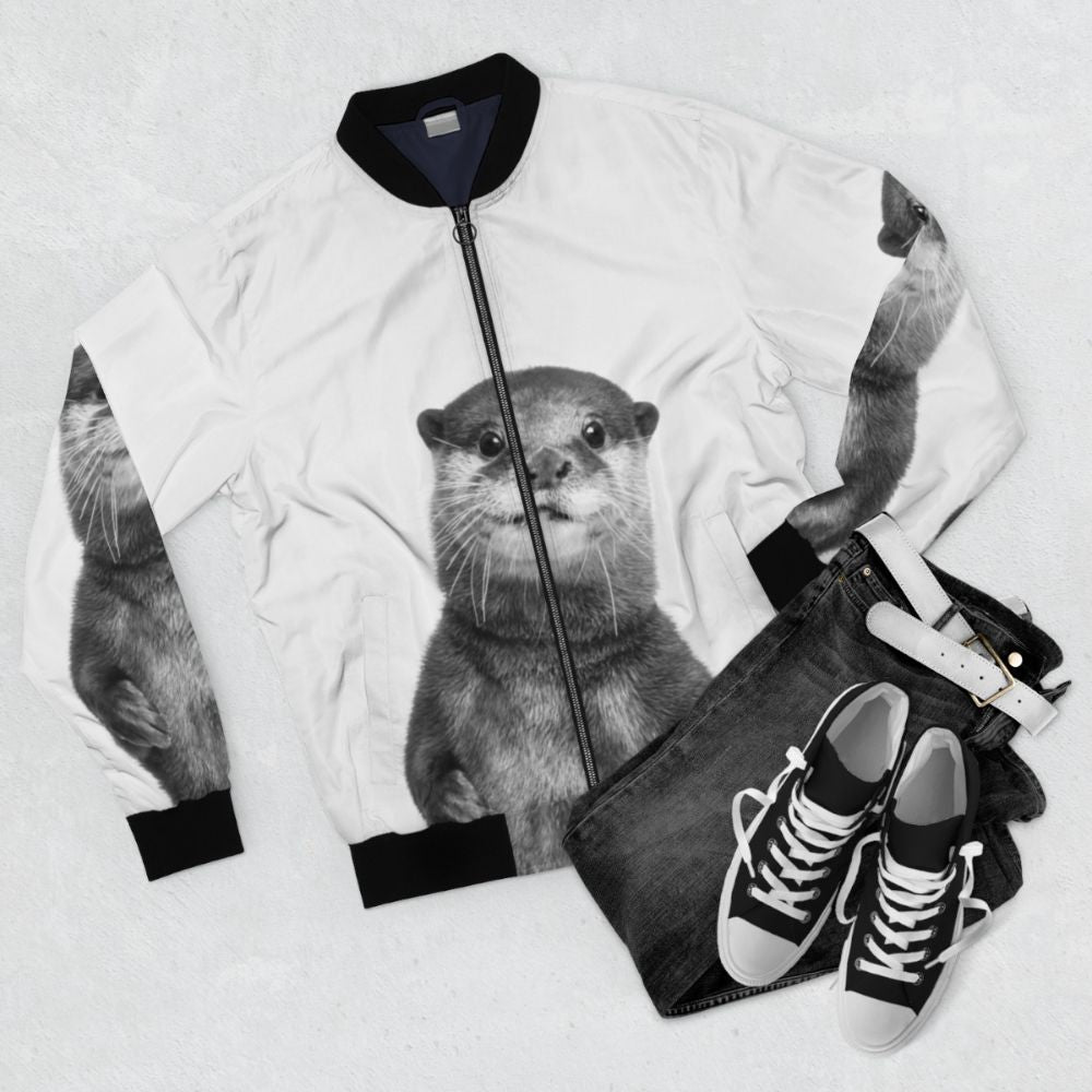 A black and white photo of a smiling otter wearing a bomber jacket, surrounded by a forest and water. - Flat lay