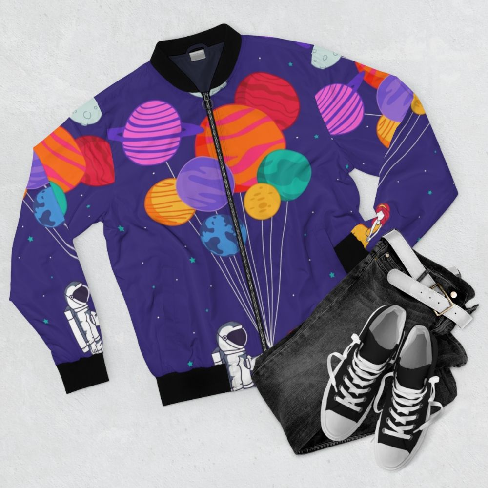 A colorful, space-themed bomber jacket with a romantic, cute design featuring planets, stars, and a couple in love. - Flat lay