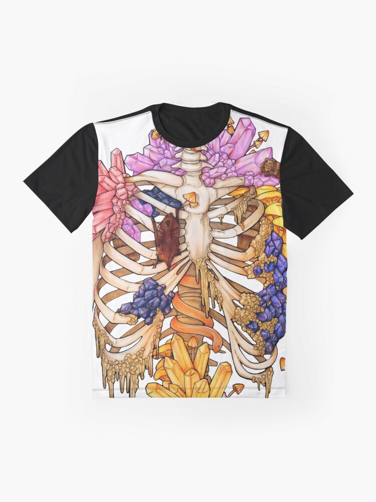 A graphic t-shirt featuring a hidden gem skeleton design in pink and purple colors, surrounded by elements like bats, snakes, mushrooms, and rocks. - Flat lay