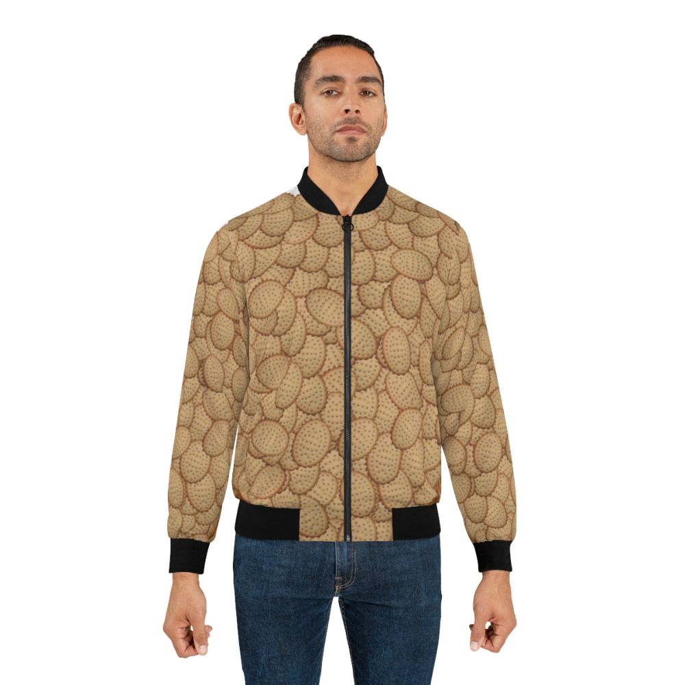 A bomber jacket featuring a collage design of chicken crimpy shapes, Arnotts biscuits, and crimpies. - Lifestyle