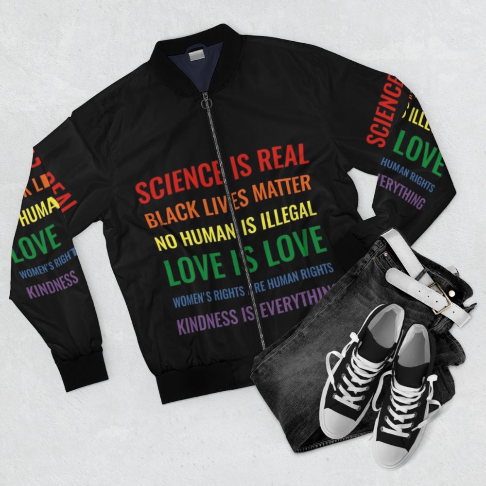 Bomber jacket with text "Science is real! Black lives matter! No human is illegal! Love is love! Women's rights are human rights! Kindness is everything!" - Flat lay