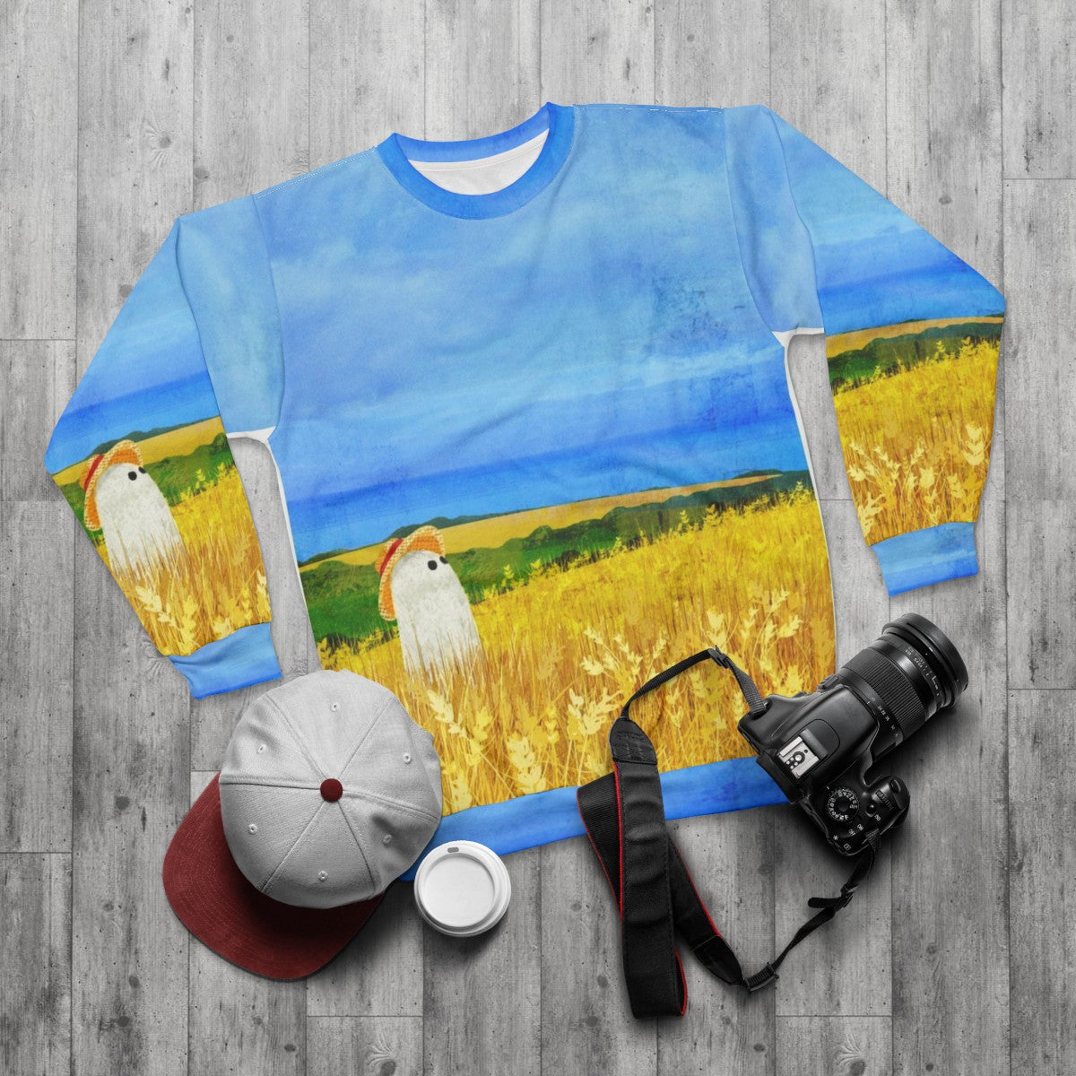 Sweatshirt with a ghostly figure in a wheat field - flat lay