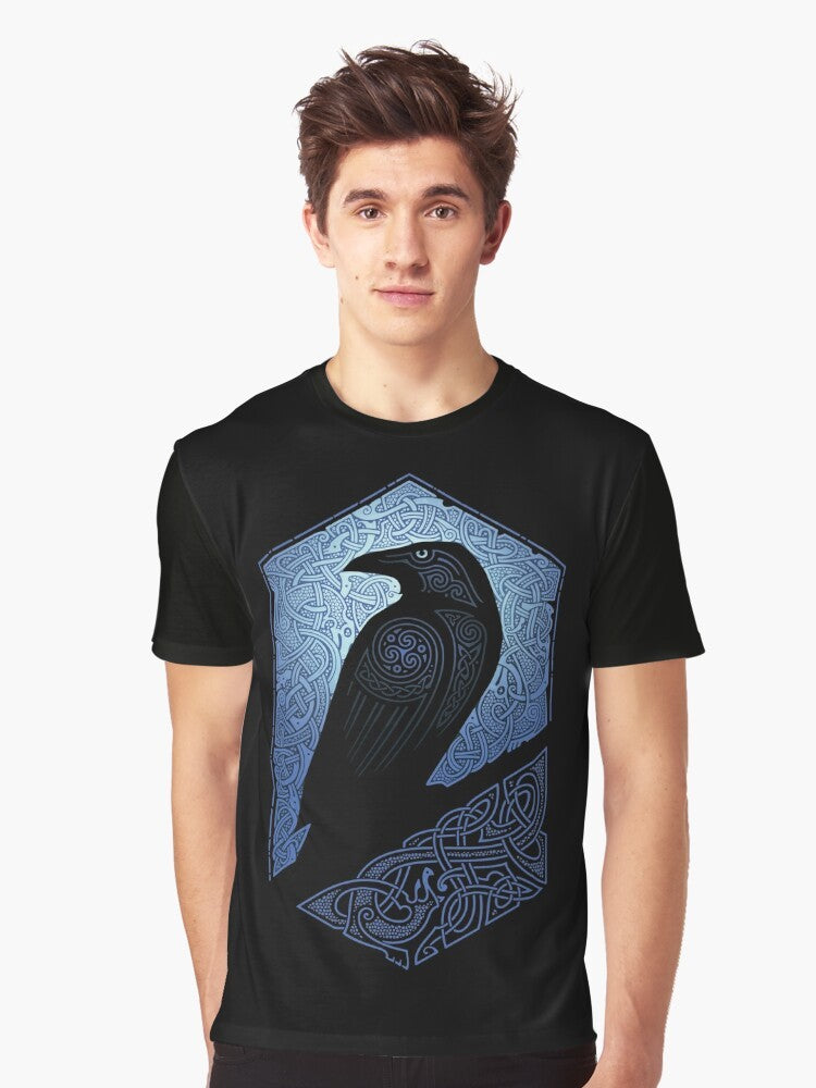 A graphic t-shirt featuring a silhouette of a raven or crow against a blue and black background with celtic and tribal design elements. - Men