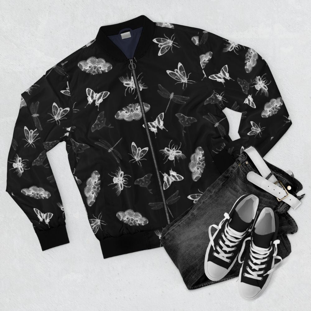 Bomber jacket with a black and white pattern of various bugs, insects, and entomology elements for a creepy, nightmare-inducing design. - Flat lay