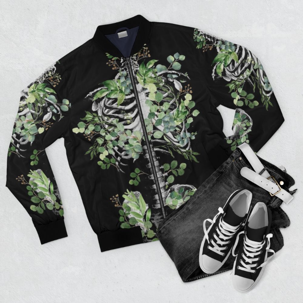 Botanical skeleton bomber jacket featuring rib cage, pelvis, and eucalyptus leaves floral design - Flat lay