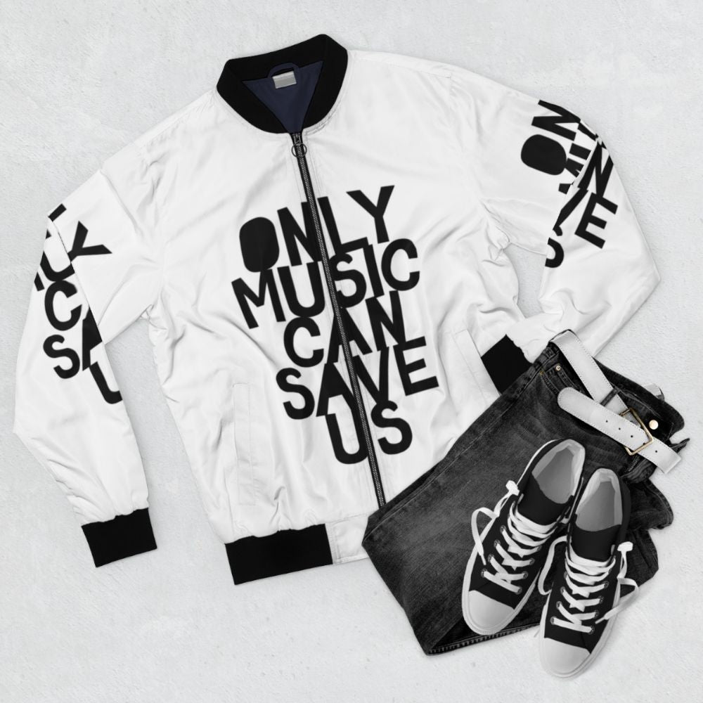 Bomber jacket with hand-drawn "Only Music Can Save Us!" typography and music-inspired design. - Flat lay