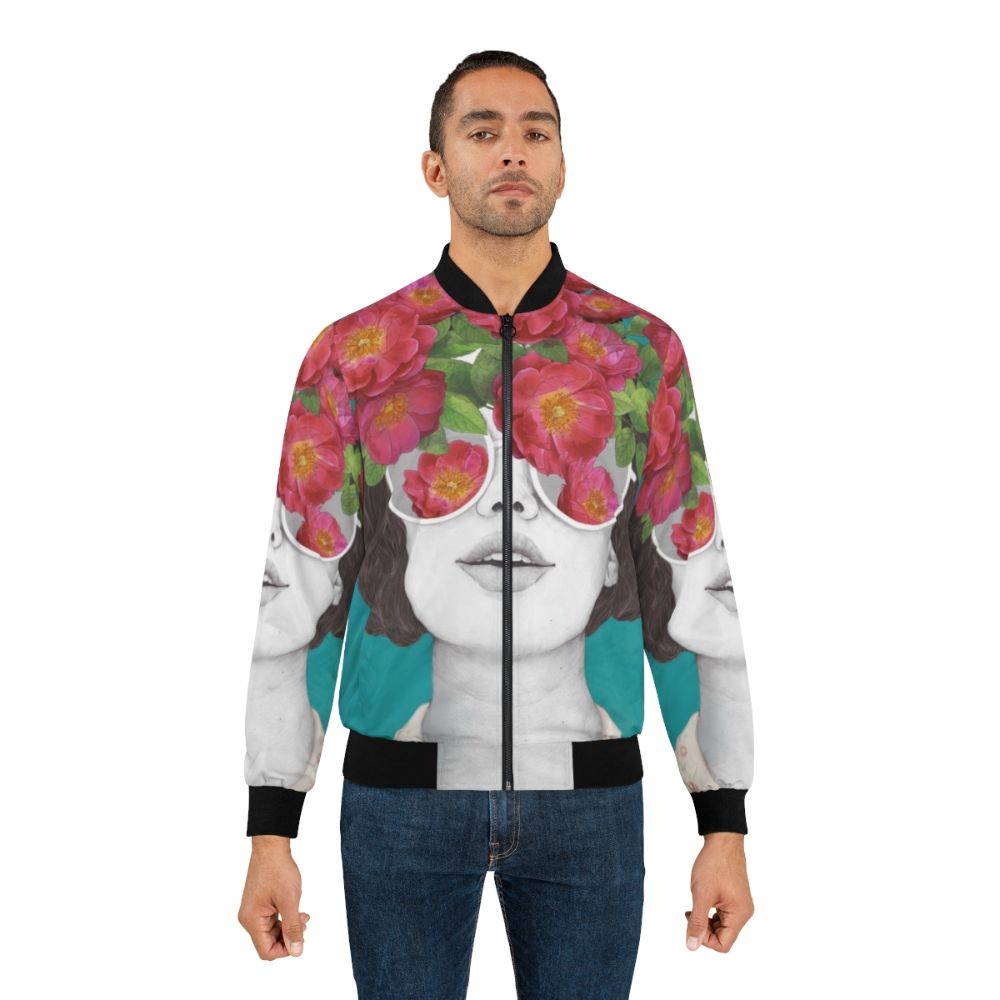 A rose-tinted watercolor bomber jacket with a surreal, abstract floral design featuring a woman's face and glasses. - Lifestyle