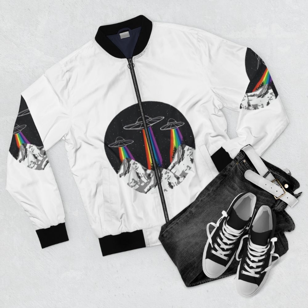 Colorful bomber jacket with a design featuring rainbow-colored mountains, a spaceship, and alien figures. - Flat lay