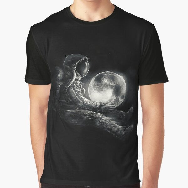 A black and white graphic t-shirt featuring a surreal, cosmic design with an astronaut or spaceman playing on the moon.