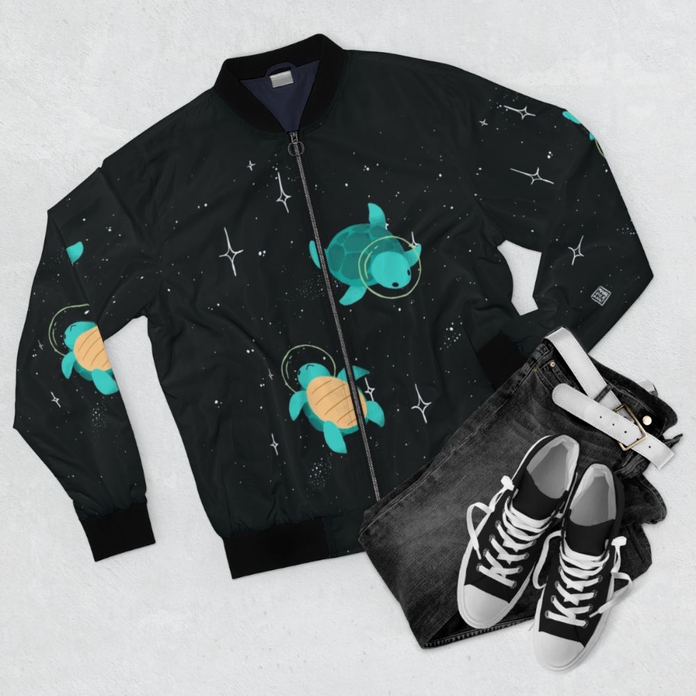 Space turtle bomber jacket with a cute, green turtle design against a starry, galaxy background. - Flat lay