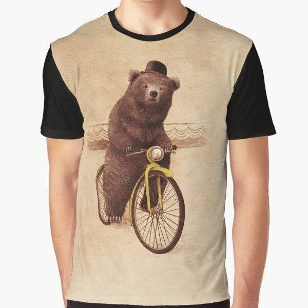 A whimsical graphic t-shirt featuring a vintage-style illustration of a bear riding a bicycle, wearing a bowler hat against a sepia-toned background.