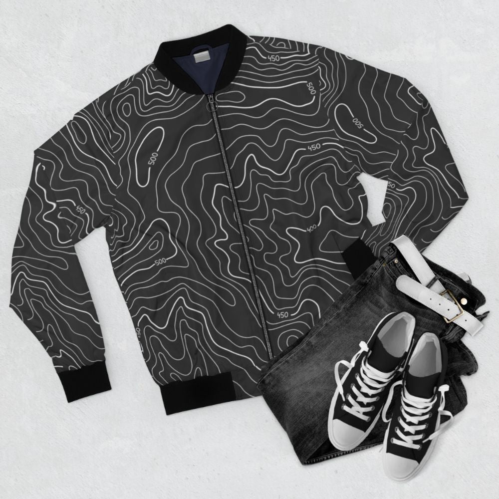 Topography bomber jacket with modern, minimalist geographical design featuring contour lines and black and white color scheme - Flat lay