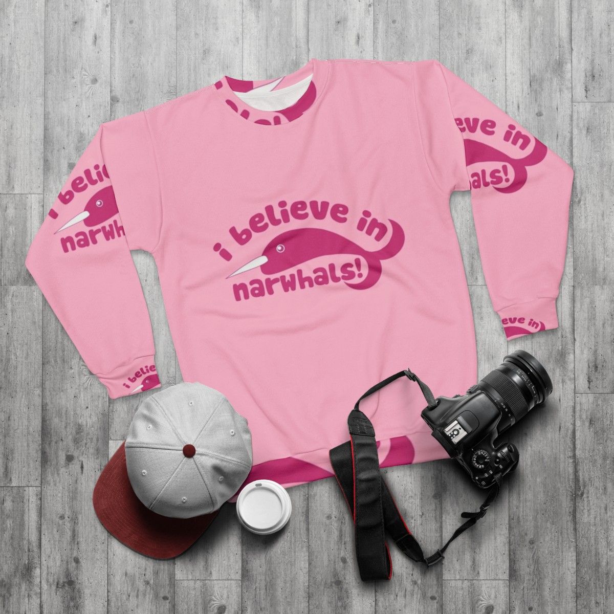 Pink sweatshirt with graphic of a cute narwhal and the text "I Believe in Narwhals" - flat lay