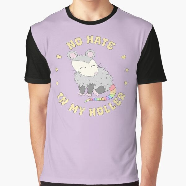 A colorful graphic t-shirt featuring a cute opossum design with the text "No Hate in My Holler" in a pastel rainbow palette.