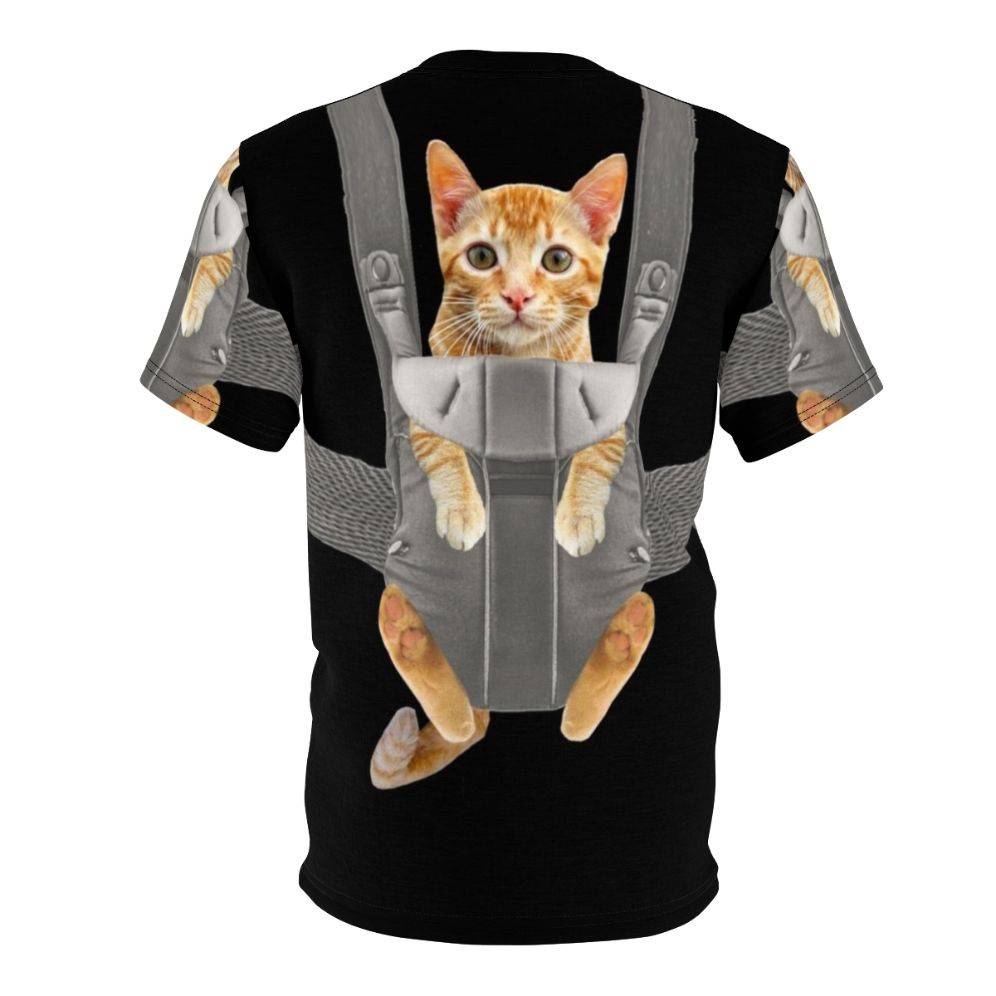 An adorable orange tabby cat named Monty sitting comfortably in a baby carrier on a t-shirt. - Back