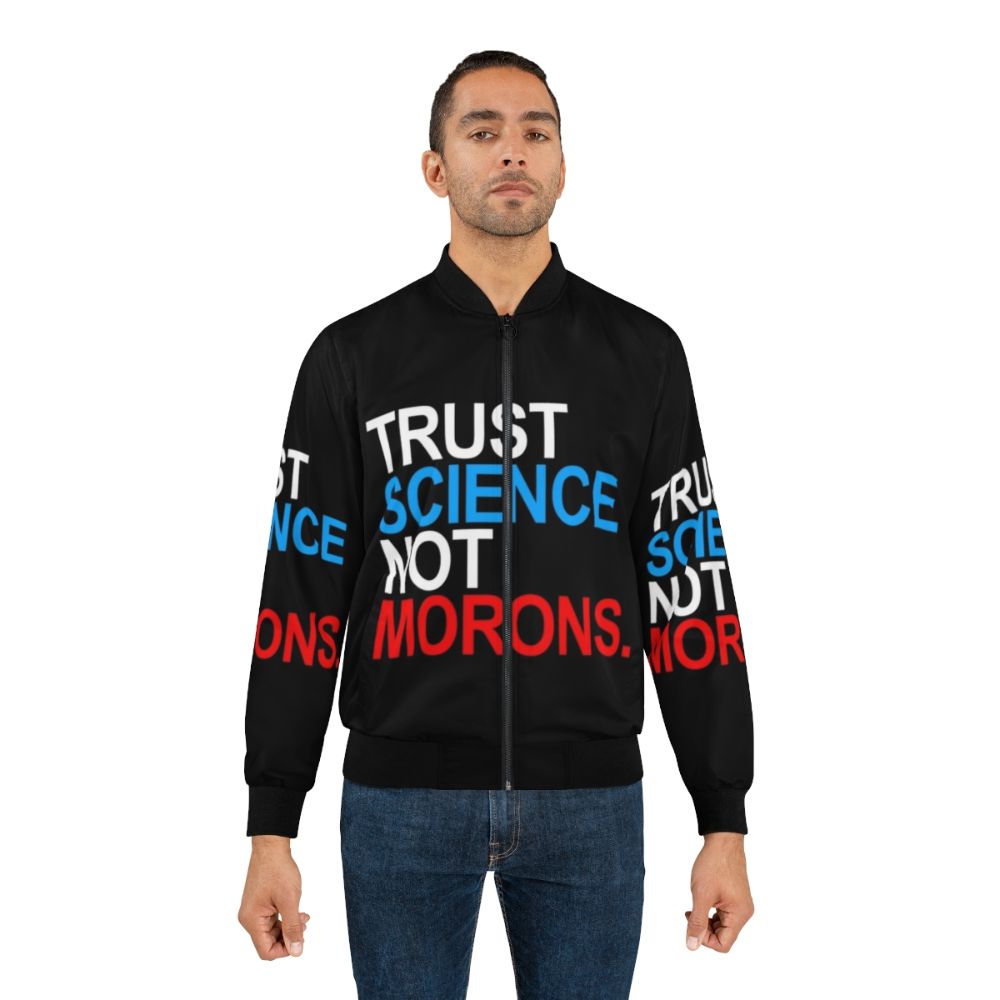 A red, white, and blue bomber jacket with the text "TRUST SCIENCE NOT MORONS" printed on it, representing a pro-science and anti-Trump sentiment during the COVID-19 pandemic. - Lifestyle