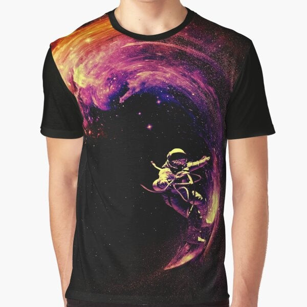 A colorful graphic t-shirt featuring an astronaut surfing through a cosmic galaxy with stars and planets in the background.