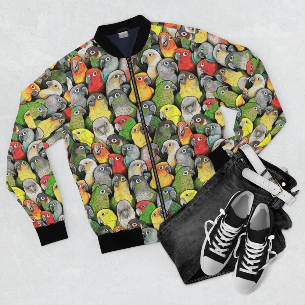 Colorful bomber jacket with a pattern featuring various conure species, including scarlet, crimson, peach faced, pineapple, and yellow sided conures. - Flat lay