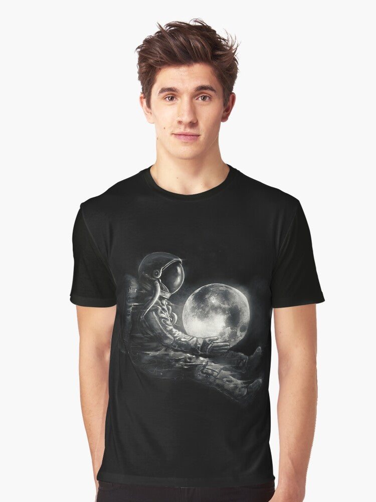 A black and white graphic t-shirt featuring a surreal, cosmic design with an astronaut or spaceman playing on the moon. - Men