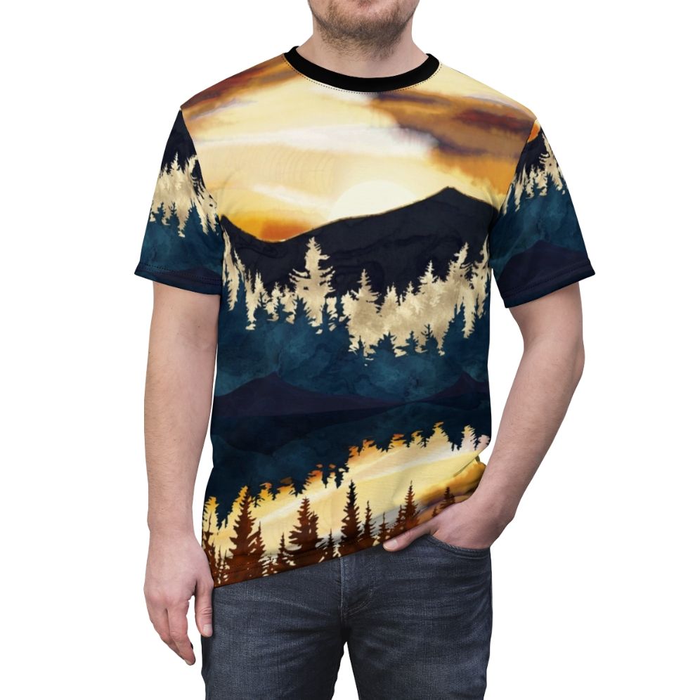 A t-shirt featuring a vibrant, watercolor-style landscape design with a beautiful fall sunset over a lake, surrounded by forests and mountains. - men front