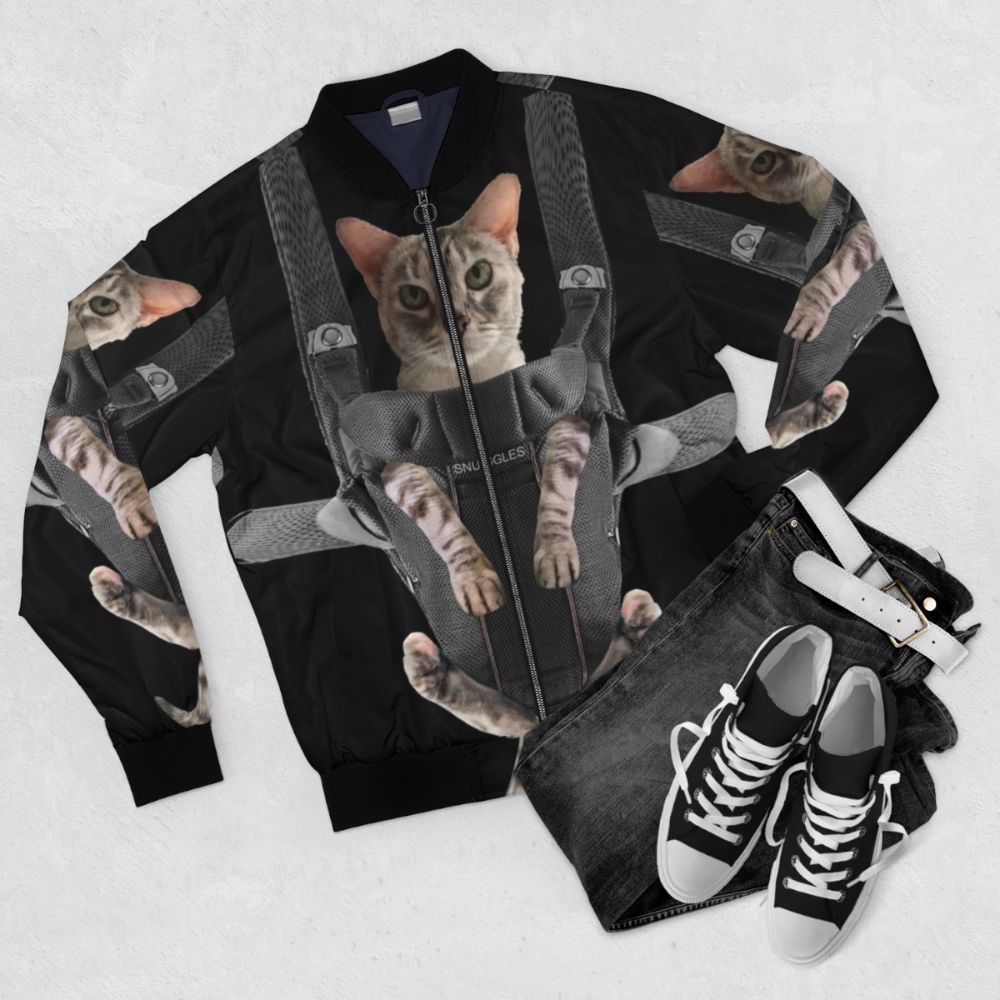 An orange cat sitting in a baby carrier on a bomber jacket - Flat lay