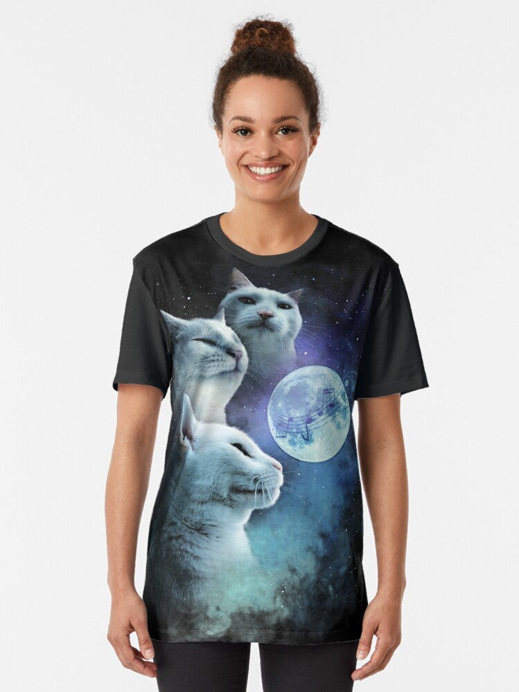 A graphic t-shirt featuring a cat vibing to music in a cosmic, galaxy-themed design with three cats and a moon. - Women