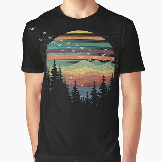 A graphic t-shirt featuring a geometric nature sunset vibes design with elements like forests, mountains, birds, and the sky.