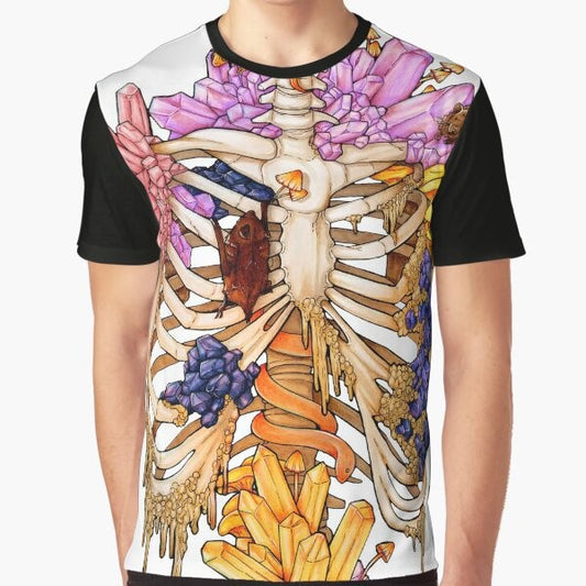 A graphic t-shirt featuring a hidden gem skeleton design in pink and purple colors, surrounded by elements like bats, snakes, mushrooms, and rocks.