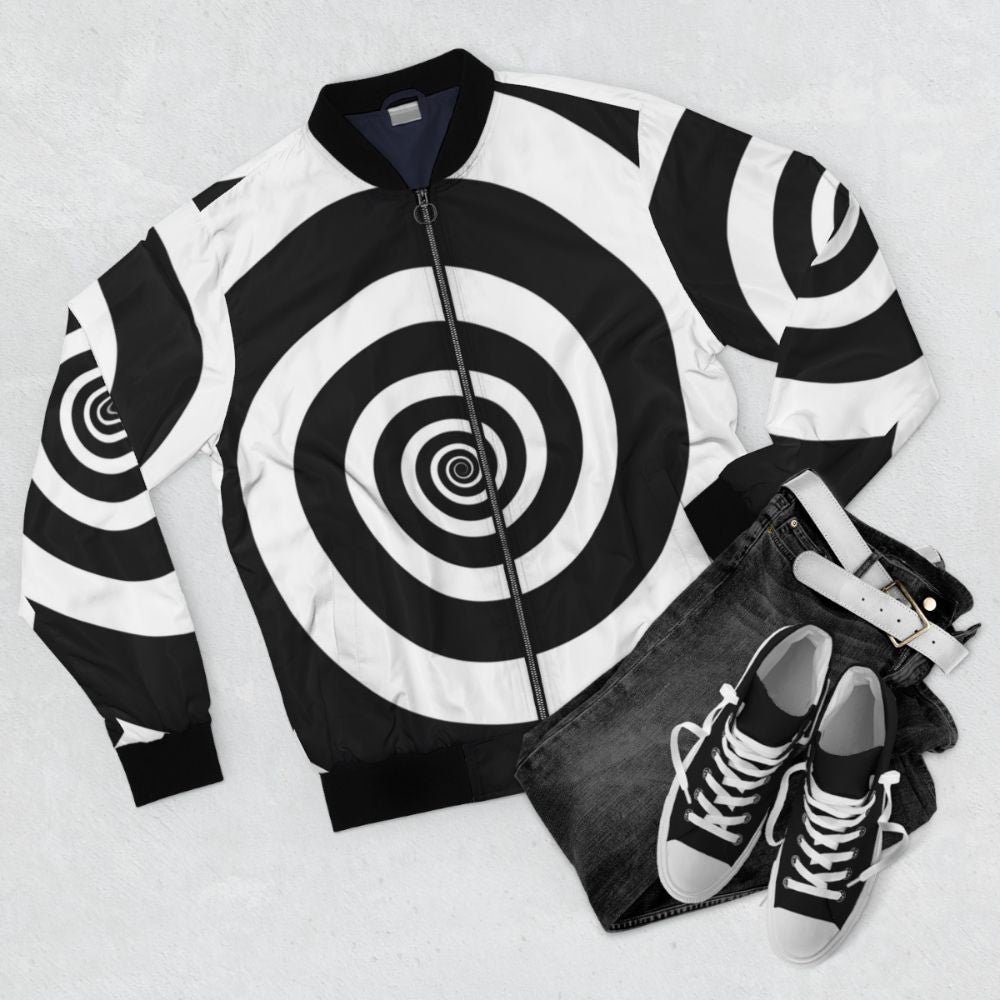 A black and white bomber jacket with a hypnotic spiral visual illusion pattern, perfect for a retro or psychedelic look. - Flat lay