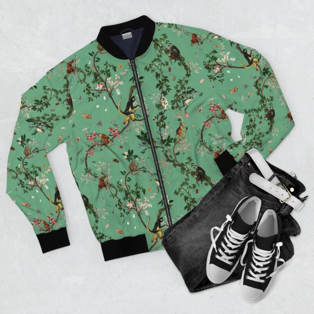 A green bomber jacket with a vibrant floral pattern, featuring monkeys and other tropical elements. - Flat lay