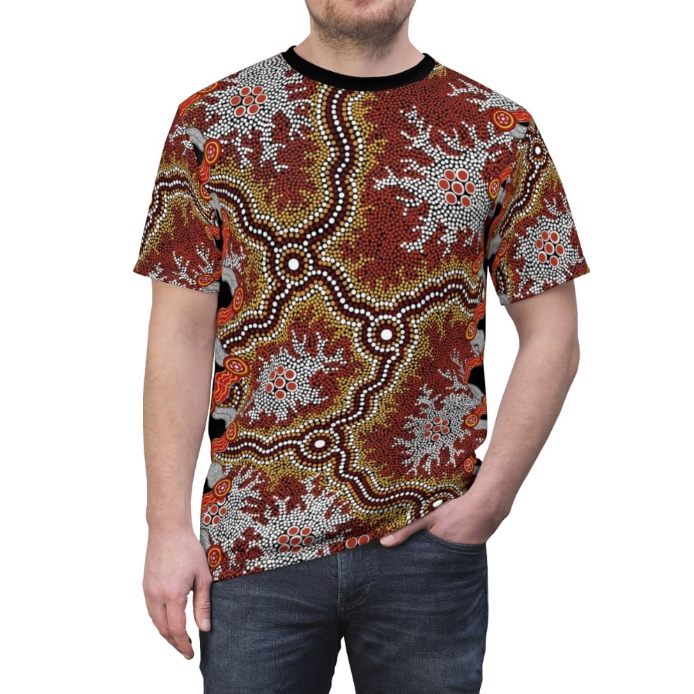 Model wearing a t-shirt featuring vibrant aboriginal art with dot patterns, emus, and bush elements. - men front