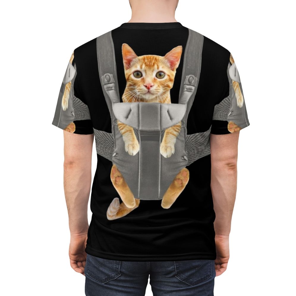 An adorable orange tabby cat named Monty sitting comfortably in a baby carrier on a t-shirt. - men back