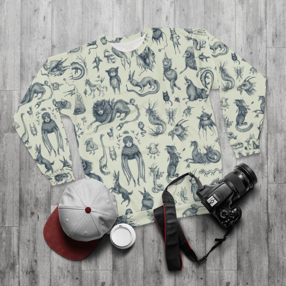 Sweatshirt with a pattern of mythical creatures like Bigfoot, Nessie, and dragons in a pastel, nature-inspired design - flat lay