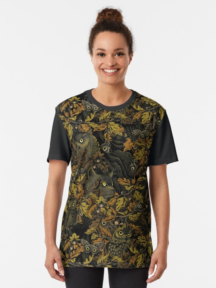 A graphic t-shirt featuring an owl design with autumn leaves, camouflage, and forest elements. - Women