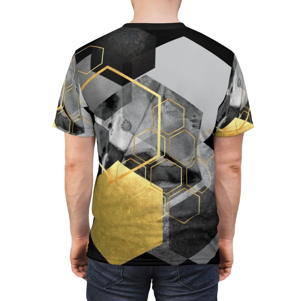 Closeup of a modern, minimalist t-shirt featuring a geometric hexagon collage design in black, white, and gold tones. - men back