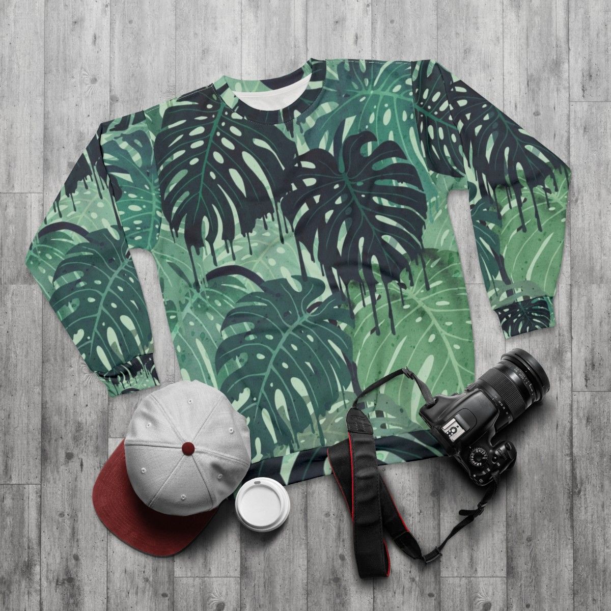 Tropical monstera leaves melting in a surreal green and blue sweatshirt design - flat lay