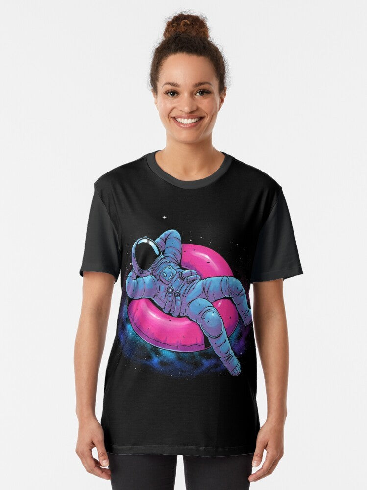 A graphic t-shirt design featuring a floating astronaut in a dreamy, cosmic space scene with stars, nebula, and other celestial elements. - Women