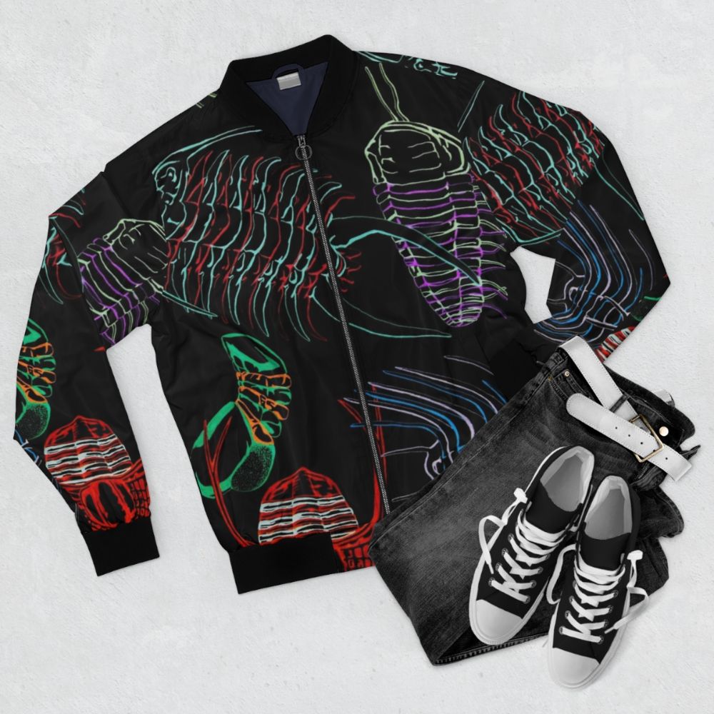 Colorful bomber jacket with hand-drawn trilobite fossil illustrations in a rainbow design - Flat lay