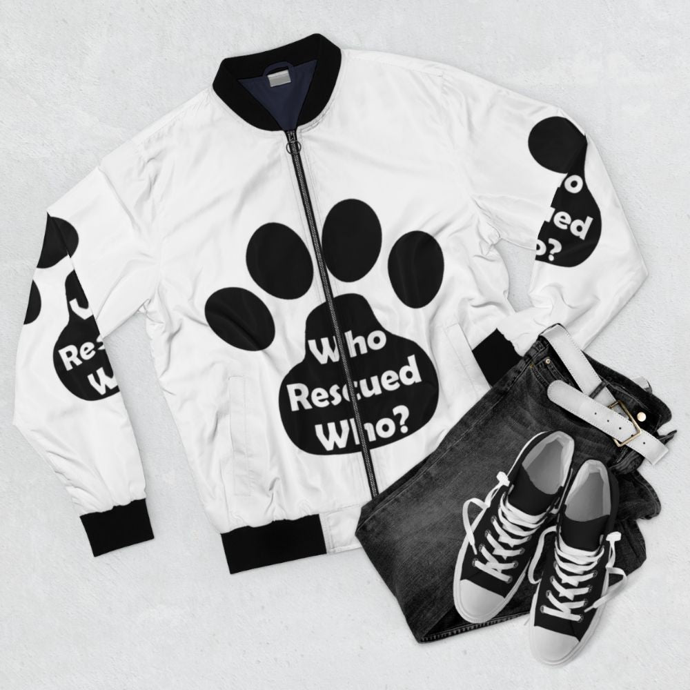 Black bomber jacket with "Who Rescued Who?" design, animal rescue theme - Flat lay