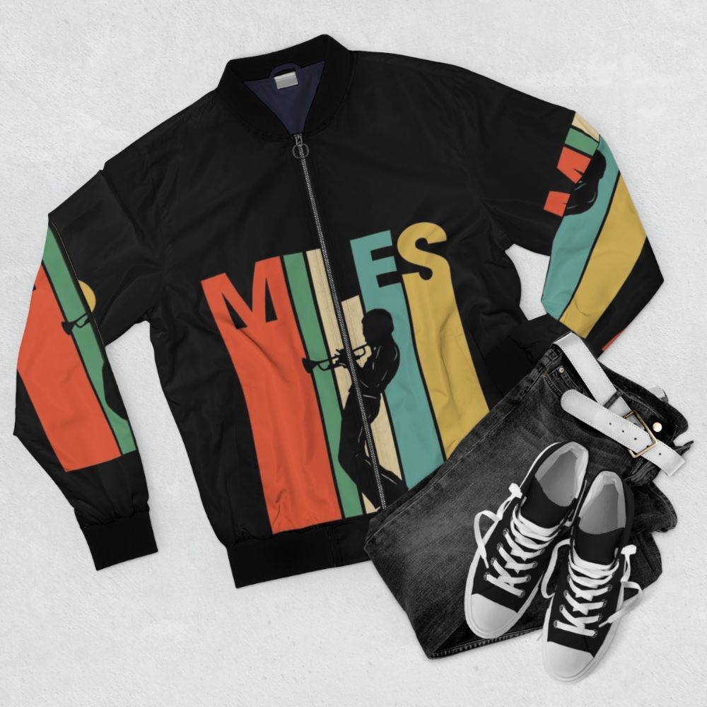 Vintage blue bomber jacket featuring the iconic trumpet and silhouette of jazz legend Miles Davis - Flat lay