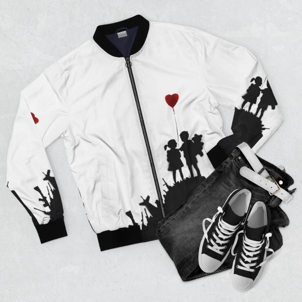 Banksy-style graffiti design with children and heart-shaped balloon against a backdrop of weapons on a bomber jacket - Flat lay