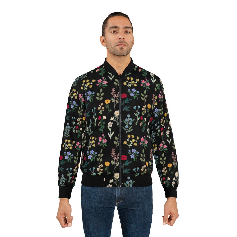 A black bomber jacket featuring a vibrant floral and botanical watercolor pattern design. - Lifestyle