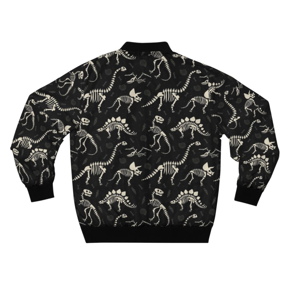 Black bomber jacket with a dinosaur fossil print design, featuring T-Rex, Triceratops, and other prehistoric creatures. - Back